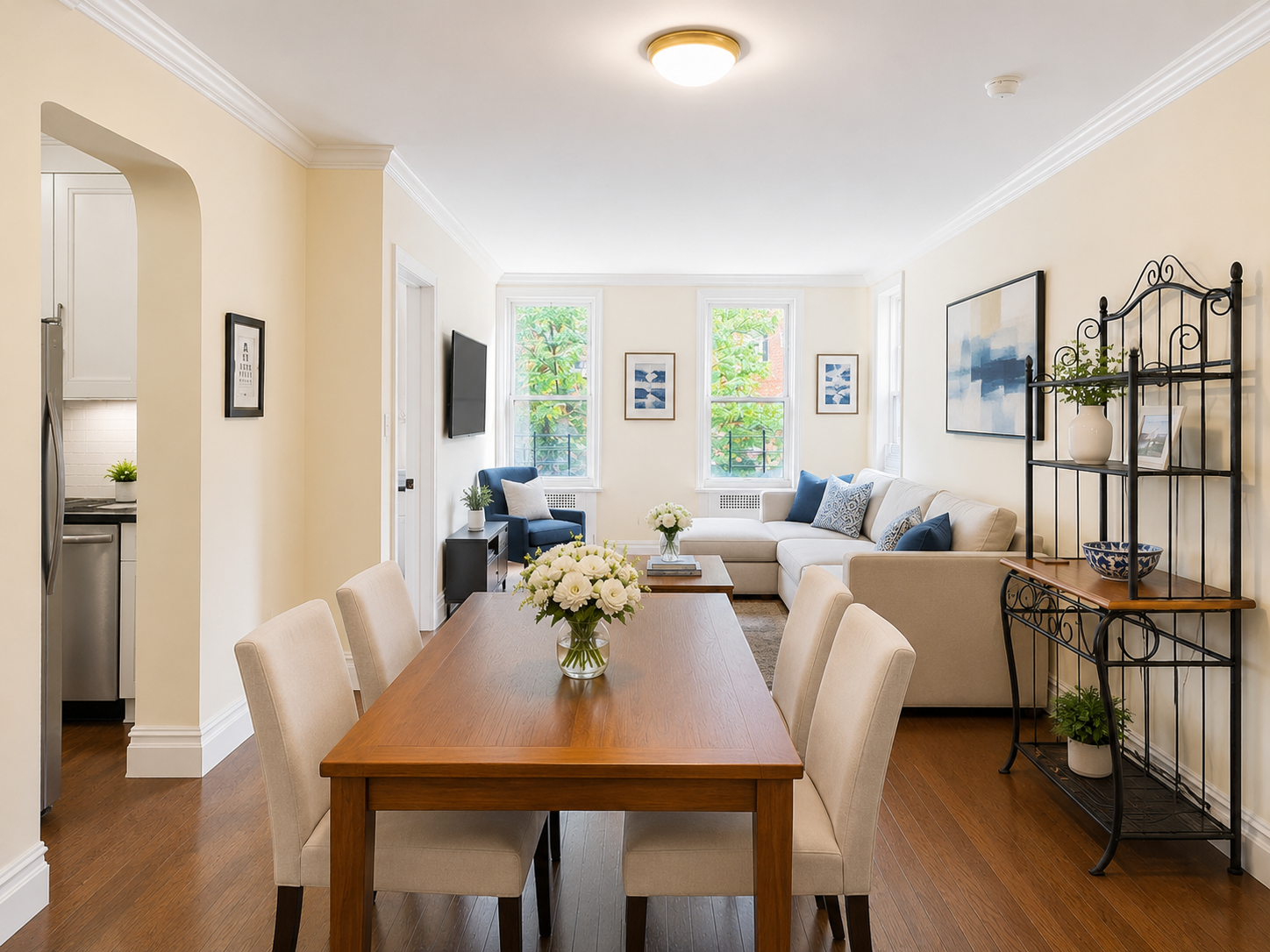 Digitally staged D32 living and dining room with three windows and leafy treetop views